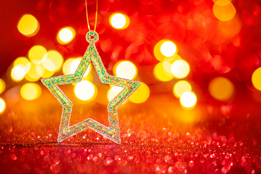 Christmas background star glitter with blurred Christmas lights on red glitter background bokeh