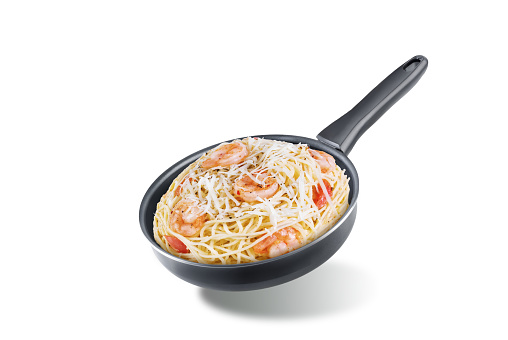 Shrimp pasta with tomatoes and cheese in a black pan on a white isolated background. toning. selective focus