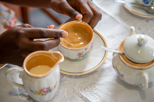 showing hands of a young woman taking cofee with vintage crockery