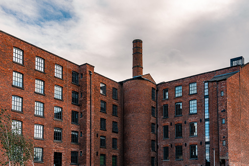 Stoke-on-Trent, UK - March 29, 2016: Two men work in yard of the historic, still-active Middleport Pottery factory in Burslem, Stoke-on-Trent, as seen from the adjacent public canal path.