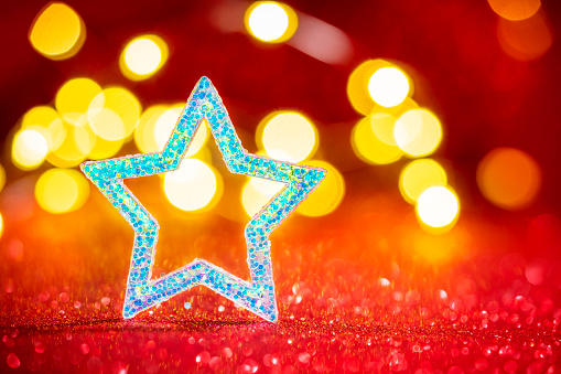 Christmas background star glitter with blurred Christmas lights on red glitter background bokeh