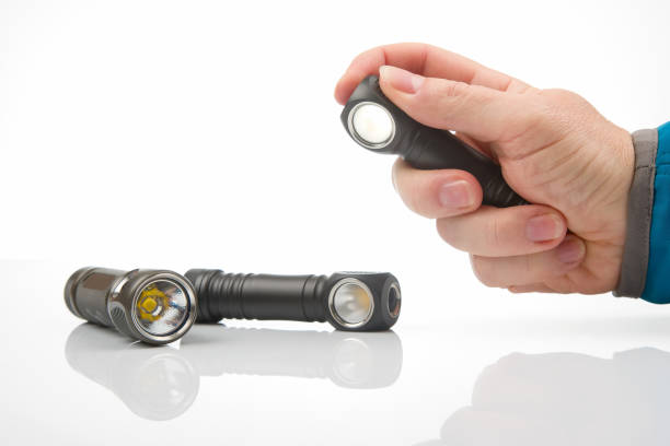 istock hand holds a flashlight against the background of other flashlights on a white background. camping and household item. 1430463003