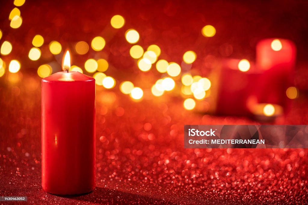 Red candle light Christmas candlelight on glowing flame sparklin Red candle light Christmas candlelight on glowing flame sparkling red background blurred Candle Stock Photo