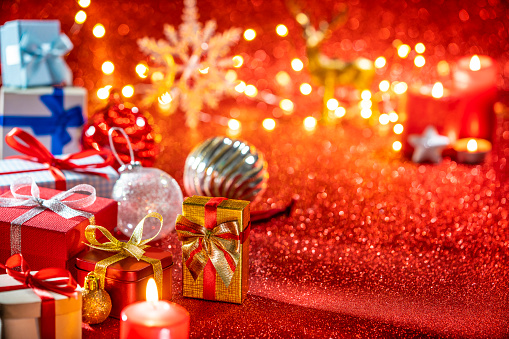 Christmas gift boxes in red reparkling background with Christmas glowing lights blurred