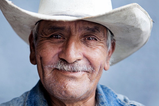 A senior man with a nice face, a nice smile and a worn in white stetson hat