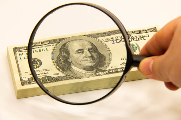 istock Stack of dollars under a magnifying glass. US dollar banknotes are enlarged with a large lens. A stack of American one hundred dollar bills. Concept of banking business and financial investment money 1430469263