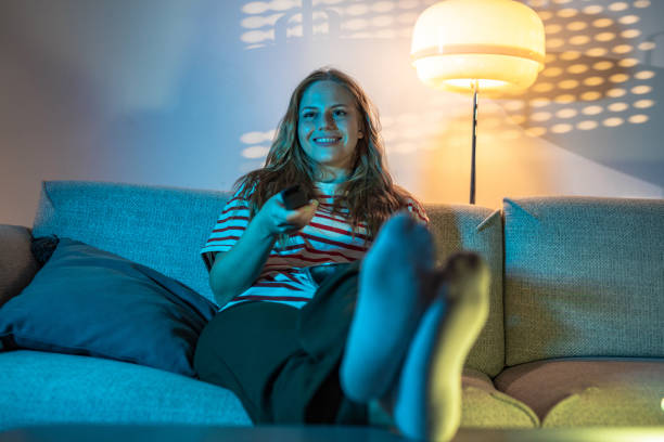 istock Smiling woman watching TV at home 1430475381
