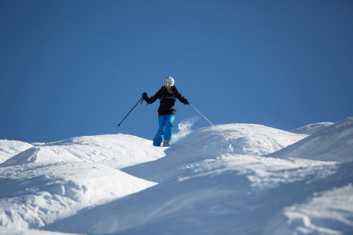 Blue and white mountain skis, sunscreen mask or ski goggles and ski boots lie on bright alpine snow. Alpine ski equipment on snow