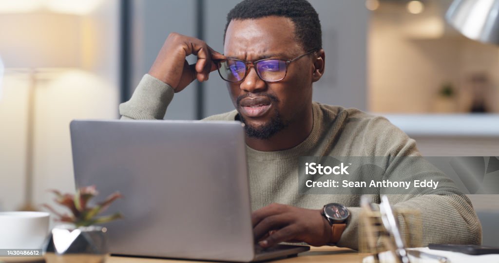 Anxiety, stress and confused man on a laptop in home office, worry and anxious about an online project deadline. Glitch, 404 and system error delay with black business man working remote, frustrated Confusion Stock Photo