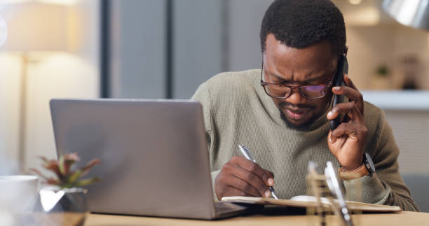 istock African man, smartphone and writing notes in office while  listening with concentration and focus. Entrepreneur in communication on phone for professional diary planning, organisation and strategy. 1430486622