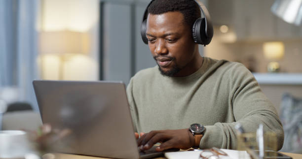 uomo nero, cuffie musicali o laptop nell'ufficio di casa o nel salotto di casa per startup creativa, webinar educativo o corso di e-learning. imprenditore con tecnologia che ascolta podcast o audio radiofonico - domestic staff audio foto e immagini stock