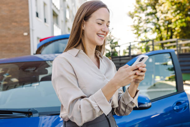 istock Young woman using smart phone by the parked car 1430487554