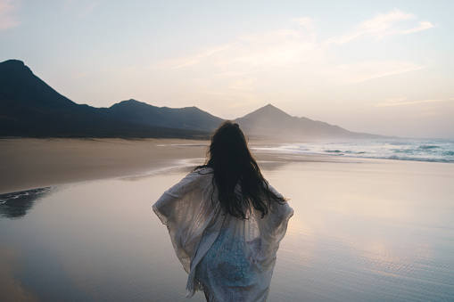 Mujer joven disfrutando de la puesta de sol en la playa - concepto wonderlust photo