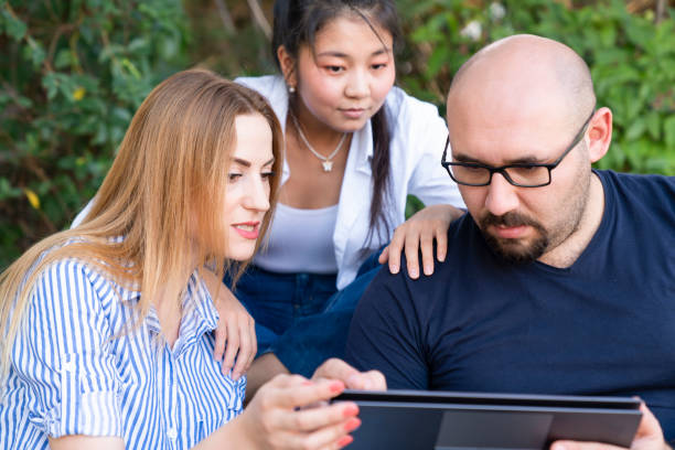 istock three people sitting in public park and using laptop 1430492982