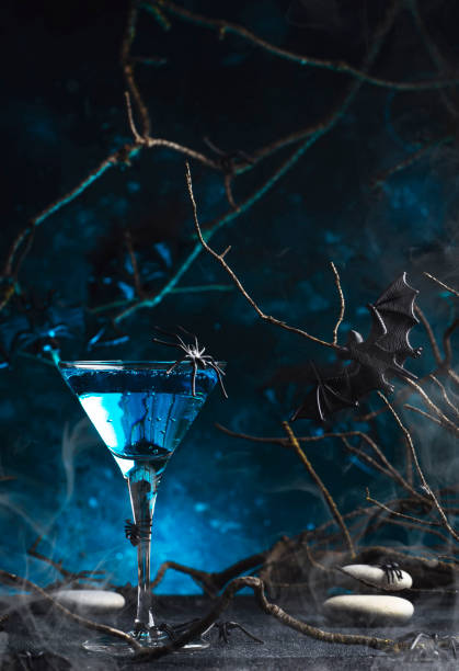 istock Halloween martini alcoholic cocktail on scary dark blue background with smoke, twisted branches, bats, stones and spiders,  festive drink for party 1430508291