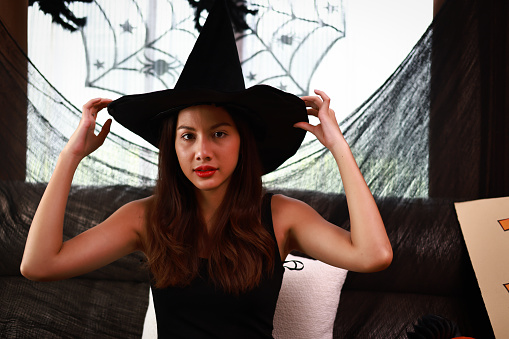 Portrait  beautiful and charming woman posing in a witch's hat in Halloween celebration .Fashion and Halloween. Make-up and cosmetics. Halloween party.