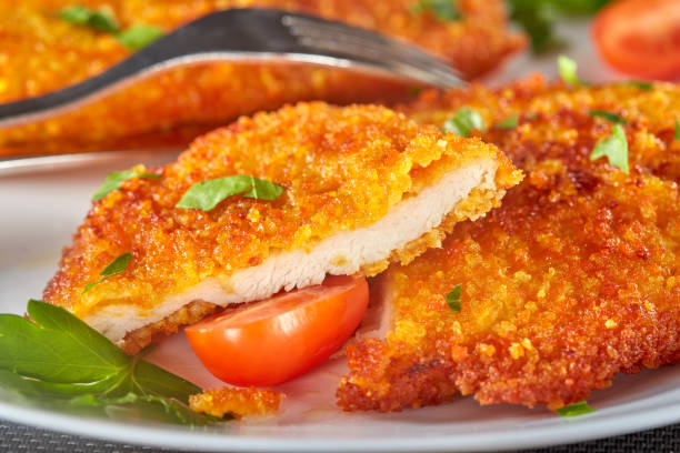 Fresh breaded chicken schnitzel with cherry tomatoes and herbs stock photo