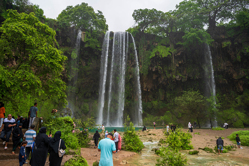 Waterfall at Ain Athum close to Salalah, Oman. The wadi becomes inundated during khareef (autumn) season where moist winds arrive from India and create a wet, rain season in the Salalah region of this arid country.\nPeople visible.