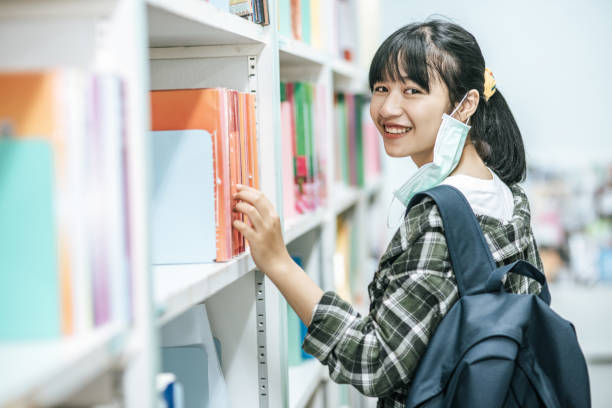 istock Women carrying a backpack and searching for books in the library. 1430535086