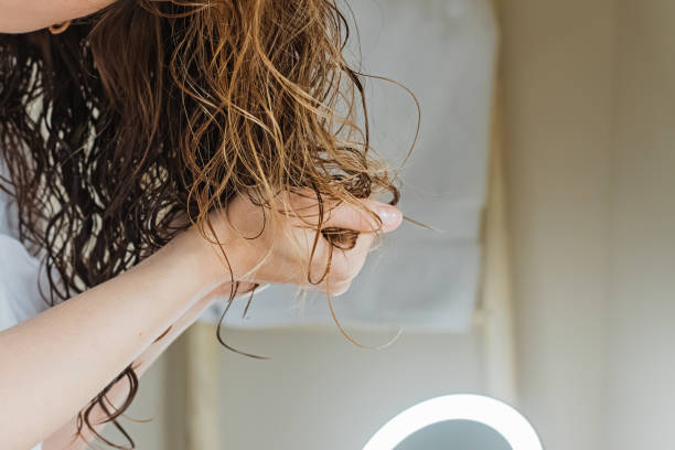kobieta chrupiąca włosy, aby utworzyć loki. stosowanie kręconej metody do stylizacji włosów. zbliżenie na dłonie - mokry włos zdjęcia i obrazy z banku zdjęć