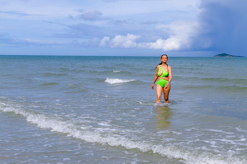Woman with swimsuit walking relax  in the rain at beach Hat Wanakon National Park, Prachuap Khiri Khan Province in Thailand is famous for travel and relax