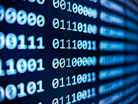 Closeup view of binary computer code with 1s and 0s displayed on a blue screen with a focus blur effect