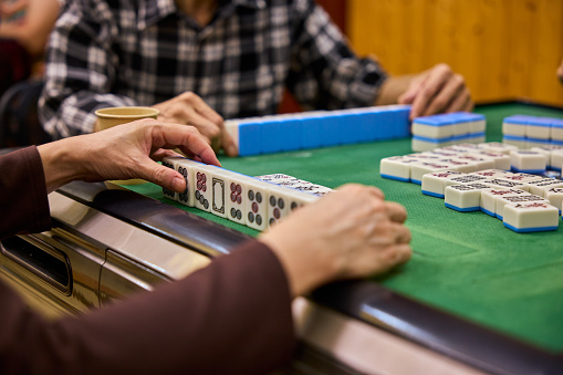 Elderly people playing mahjong, indoor gamble activity at home during spring festival.