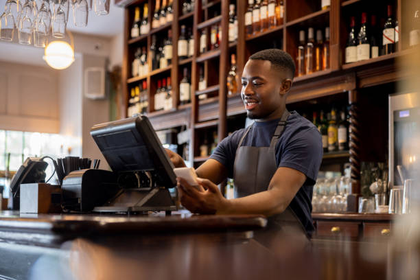 Waiter placing an order in the system using a computer Happy waiter working at a restaurant and placing an order in the system using a computer point of sale stock pictures, royalty-free photos & images