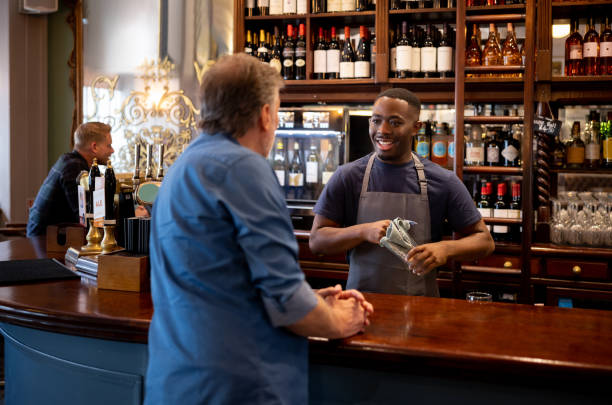 istock Waiter cleaning a glass while talking to a customer at the pub 1430548773