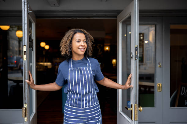 istock Happy waitress opening the doors of a restaurant 1430548781