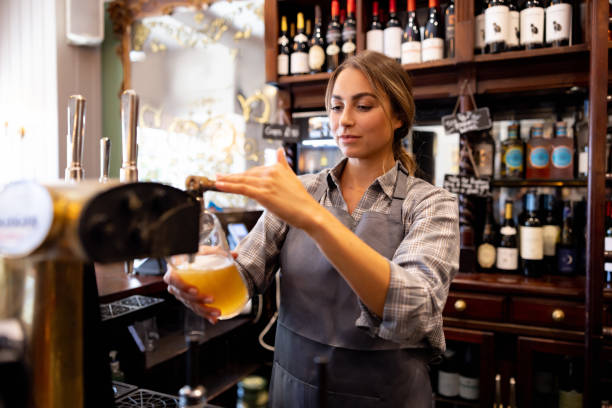 bartender serving beer from the tap at the pub - beer pub women pint glass imagens e fotografias de stock