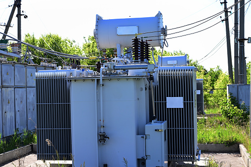 Three electricity pylons in front of a coal-fired power plant with pollution.