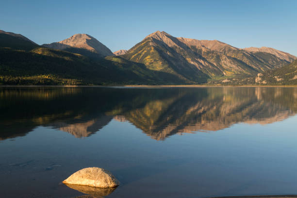 Mount Hope and Twin Peaks rise above the reflection on Twin Lakes in Central Colorado. stock photo