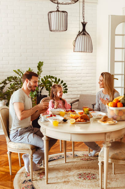 Happy young family having breakfast at home