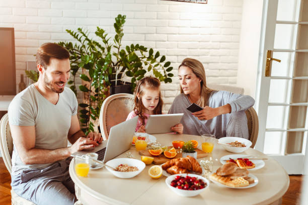 istock Young happy family having a breakfast and using modern technology 1430554026