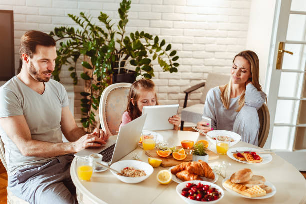 istock Young happy family having a breakfast and using modern technology 1430554037