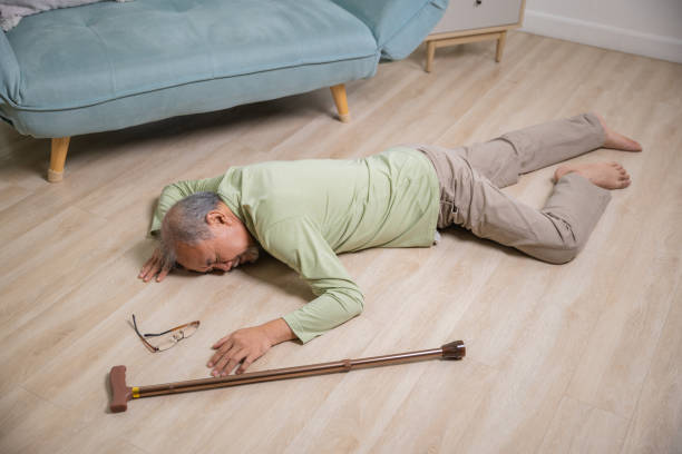 istock Asian senior man falling down lying on floor at home alone with wooden walking stick 1430560512