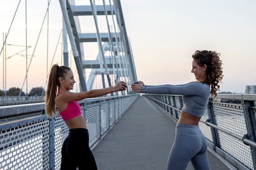 Two young woman exercise outdoor with weights on hands after jogging