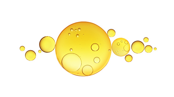 Golden yellow abstract oil bubbles or face serum isolated on white background. Oil bubbles macro photography.