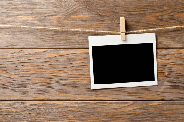 istock An empty photo is hanging on a rope. A design element. Brown wooden background. Copy space. 1430573620
