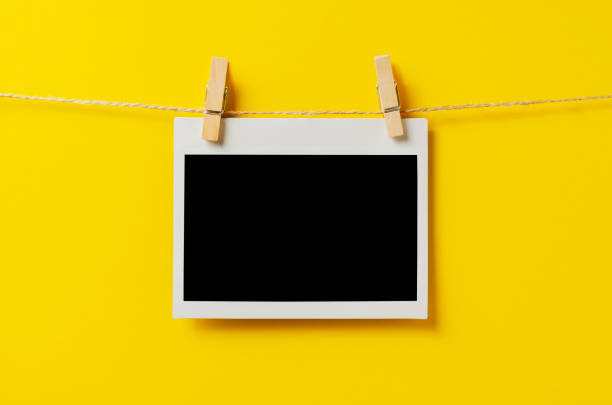 istock An empty photo is hanging on a rope with a clothespin. A design element. Yellow background. Copy space. 1430573631