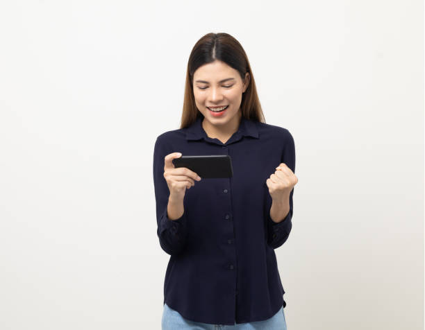 istock Pretty young mixed race woman using smartphone standing on isolated white background. She texting on cell phone. Feeling happy and excited 1430580209