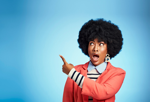 Wow, deal and black woman hand pointing to advertising and marketing space or mock up on blue mockup studio background. Surprise Afro female showing important message, information sign or gesture