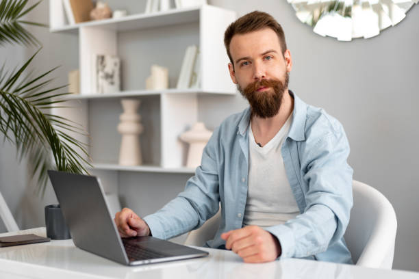 istock Stylish bearded man working on laptop from home sitting at the table 1430581334