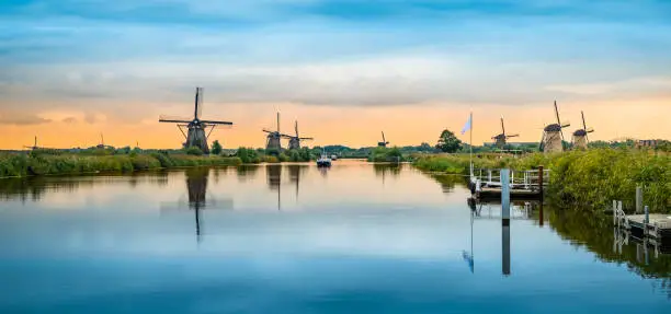 Wide image with historic windmills of Kinderdijk reflecting in the canal, Alblasserwaard polder, South Holland, Netherlands. Popular travel destination. Unesco World Heritage site.