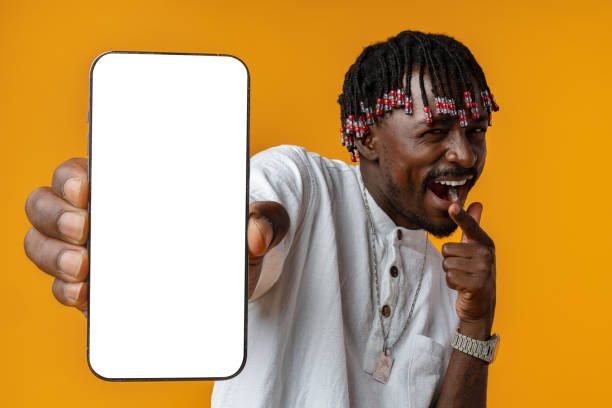 istock Excited young african man holding smartphone with white blank screen in hand on yellow studio background 1430584087