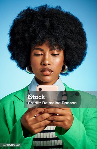 istock Black woman with phone reading social media, news or post online and text message to contact against blue mock up studio background. Afro model on the internet with a mobile smartphone app with 5g 1430588548