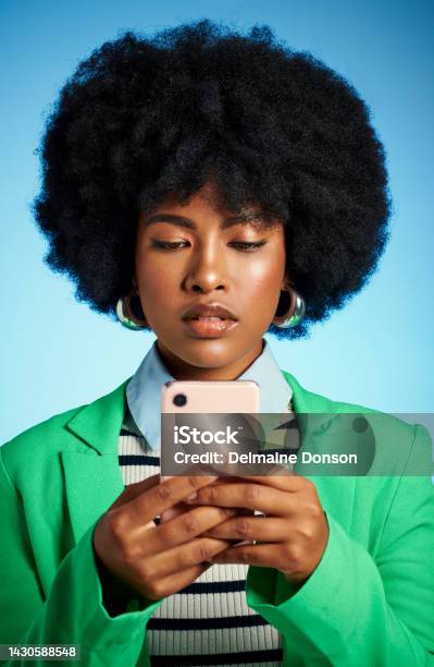 Black Woman With Phone Reading Social Media News Or Post Online And Text Message To Contact Against Blue Mock Up Studio Background Afro Model On The Internet With A Mobile Smartphone App With 5g Stock Photo - Download Image Now