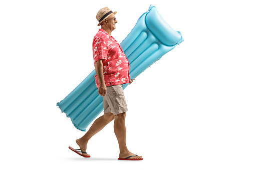 Foto de perfil de cuerpo entero de un turista masculino maduro que lleva un colchón inflable y camina photo