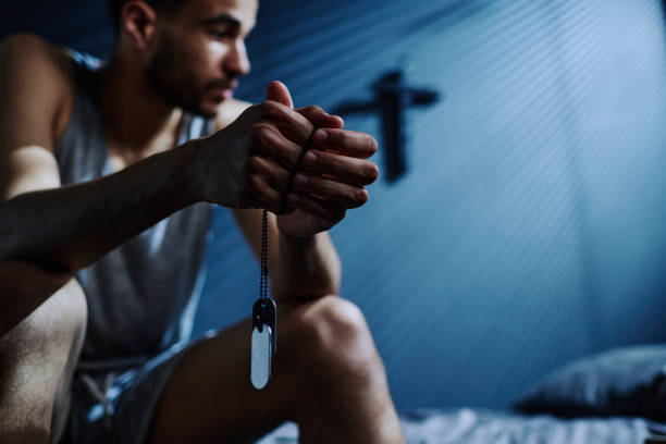 Hands of young insomniac man holding silver chain with medallions Hands of young insomniac man holding silver chain with medallions while sitting on bed after sleepless night and thinking of something locket photos stock pictures, royalty-free photos & images